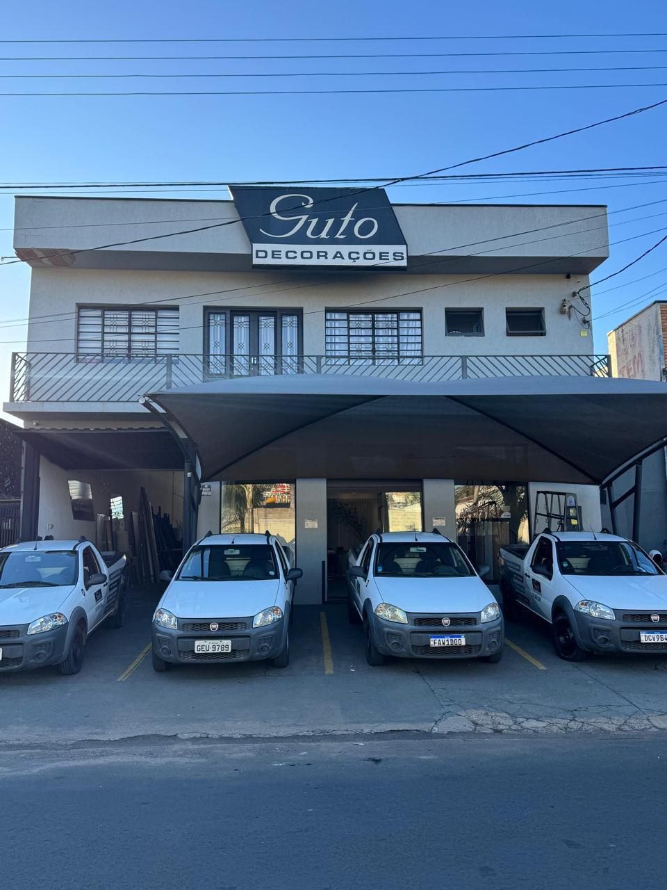 Fachada da loja Guto Decoracoes com a frota de veiculos